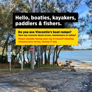 A view of the Holden Street Boat Ramp, a beach launch point in Vincentia, showing an ageing asphalt surface that runs directly onto rocks and sand, with trees along the edge and Jervis Bay visible in the background. Text over image reads: ‘Hello, boaties, kayakers, paddlers & fishers. Do you use Vincentia’s boat ramps? Have any concerns about access, maintenance or safety? Please consider having your say in Council’s boating infrastructure survey, closing 17 July